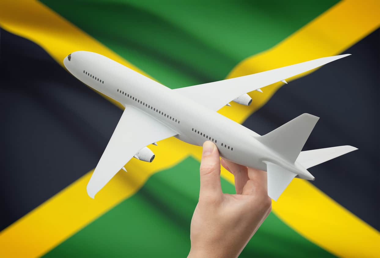 Airplane in hand with flag on background - Jamaica