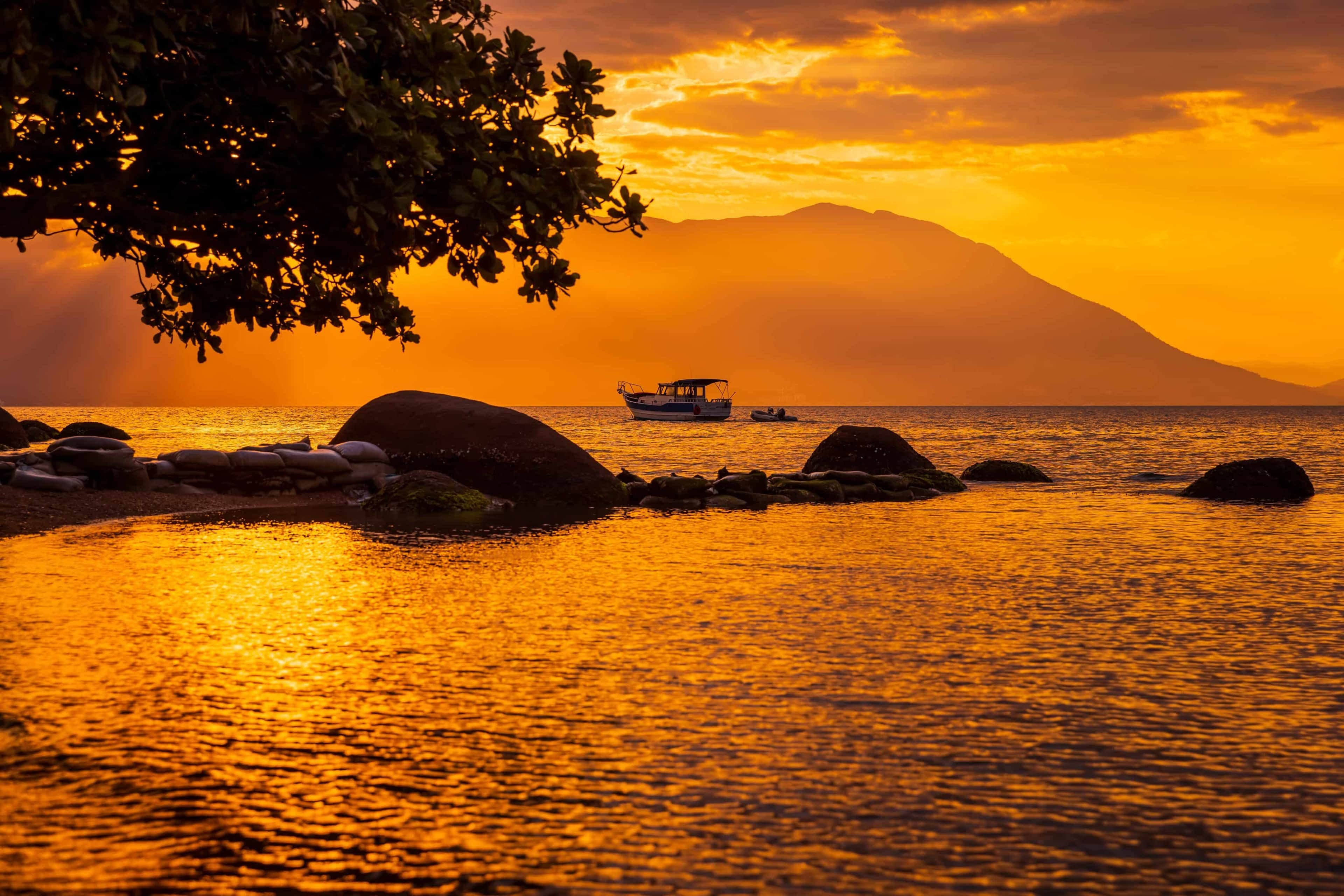 Warm,Sunset,On,Beach,And,Quiet,Ocean,With,Boat,In